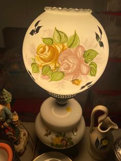 a vase with flowers painted on it next to other dishes and cups in a display case