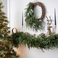 a christmas mantle decorated with greenery, candles and wreaths on top of it