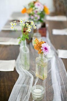 three vases filled with flowers sitting on top of a table