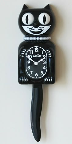 a black cat clock with pearls on it's face is hanging from the wall