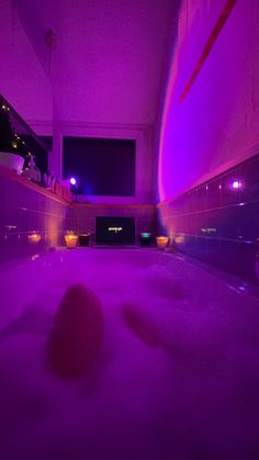 a bath room with a large tub filled with water and purple lights on the walls