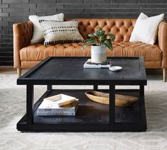 a living room with a couch, coffee table and pillows on the floor in front of a brick wall