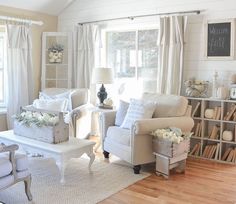 a living room filled with white furniture and lots of bookshelves on the wall