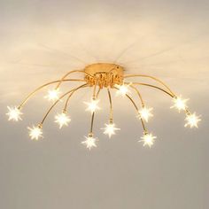 a ceiling light with stars hanging from it's center and the lights turned on