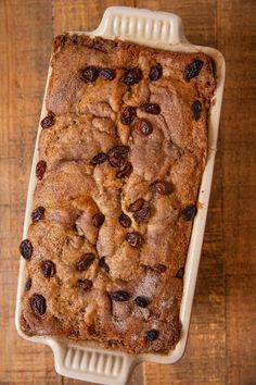 a loaf of bread sitting on top of a wooden table with raisins in it