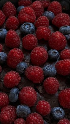 fresh raspberries and blueberries on top of a chocolate cake