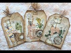 three tags with flowers are hanging on a lace covered tablecloth, one is empty and the other has an old clock