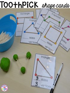 several different shapes and sizes of sticks on a table next to a blue container with strawberries