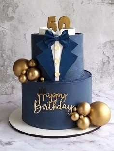 a blue birthday cake with gold decorations and a bow tie on top that says happy birthday