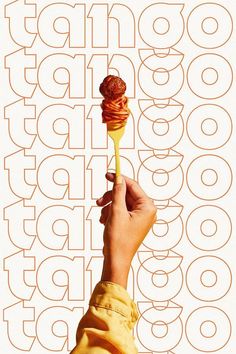 a hand holding a pastry on a stick in front of an orange and white background