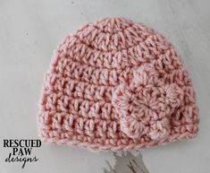 a pink crocheted hat sitting on top of a white table