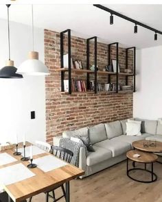 a living room filled with furniture next to a brick wall covered in bookshelves