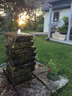 a stack of rocks sitting on top of a lush green field next to a house