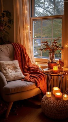 a living room with candles lit on the floor and a chair in front of a window