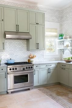 a kitchen with green cabinets and silver appliances