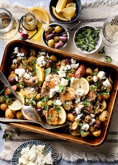 a dish with potatoes, olives, and feta cheese on it next to other dishes