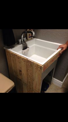 a person is holding the edge of a sink in front of a wooden counter top