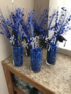 blue glass vases with silver and black paper cutouts on them sitting on a counter