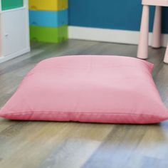 a pink pillow sitting on top of a wooden floor