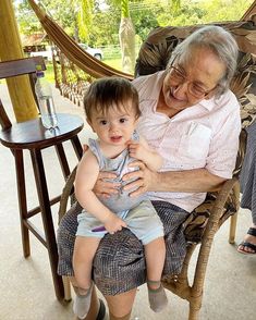 an older woman sitting in a chair holding a small child