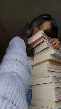 a woman is hiding her face behind a stack of books