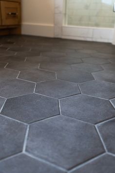 the bathroom floor is made up of hexagonal tiles and gray grouting