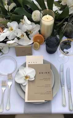 the table is set with white flowers and place settings for an elegant dinner or brunch