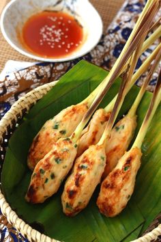 chicken skewers on a banana leaf with dipping sauce