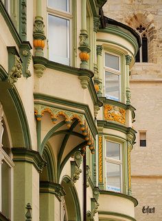 an old building with green trim and ornate decorations on the front, side and top