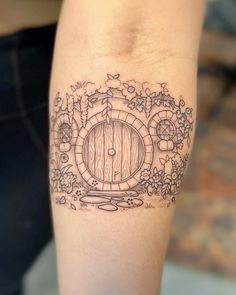 a tattoo on the arm of a person with a barrel and flowers around it,