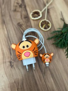 an orange and white tiger head plugged in to a charger on top of a wooden table