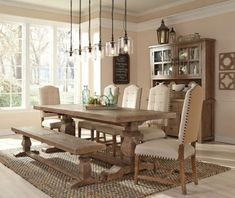 a dining room table with chairs and a bench in front of it on a rug