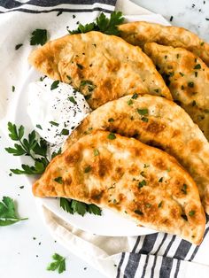 three pita breads on a plate with sour cream and parsley garnish