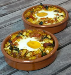 two brown bowls filled with food sitting on top of a wooden table next to each other