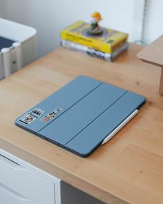 a wooden desk topped with a blue laptop computer sitting on top of a wooden table