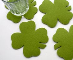 four green felt shamrocks next to a glass of water