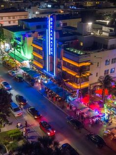 an aerial view of a city street at night with cars parked in front of the building