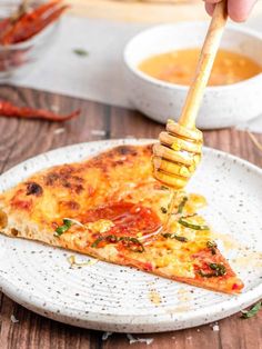 a slice of pizza on a white plate with a honey stick sticking out of it