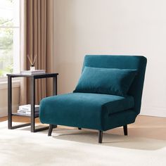 a blue chair sitting on top of a white rug in a living room next to a window