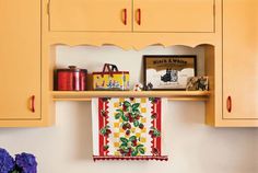 a kitchen with yellow cabinets and colorful towels hanging from the shelf above it's sink