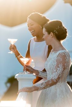 two women standing next to each other holding wine glasses in their hands and smiling at each other