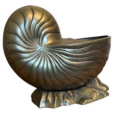 a bronze shell shaped vase sitting on top of a rock