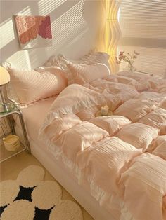 an unmade bed with pink comforter and pillows on top of it in a bedroom