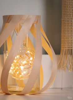 a glass lantern with string lights in it on a table next to a lamp shade