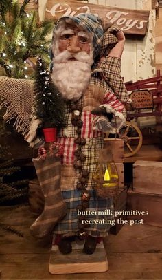 an old fashioned christmas decoration with a santa clause holding a potted plant and standing next to a tree