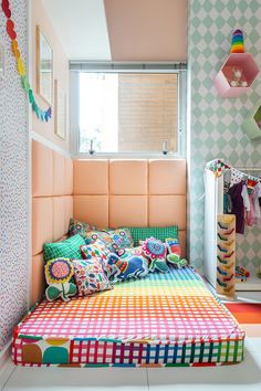 a bed with colorful sheets and pillows in a room that has geometric wallpaper on the walls