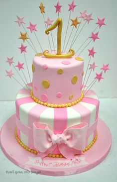 a pink and white birthday cake with stars on the top, one candle in the shape of a number