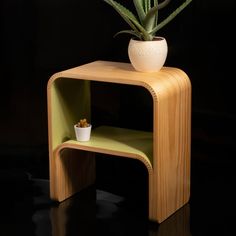 a potted plant sitting on top of a small wooden shelf next to a black wall