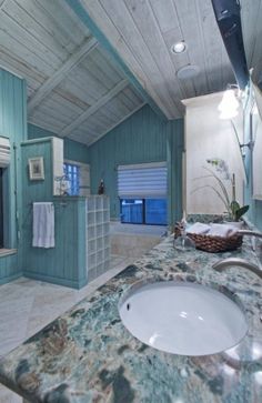 a bathroom with marble counter tops and blue walls