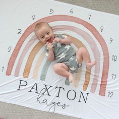 a baby laying on top of a blanket with the name paxton in front of it